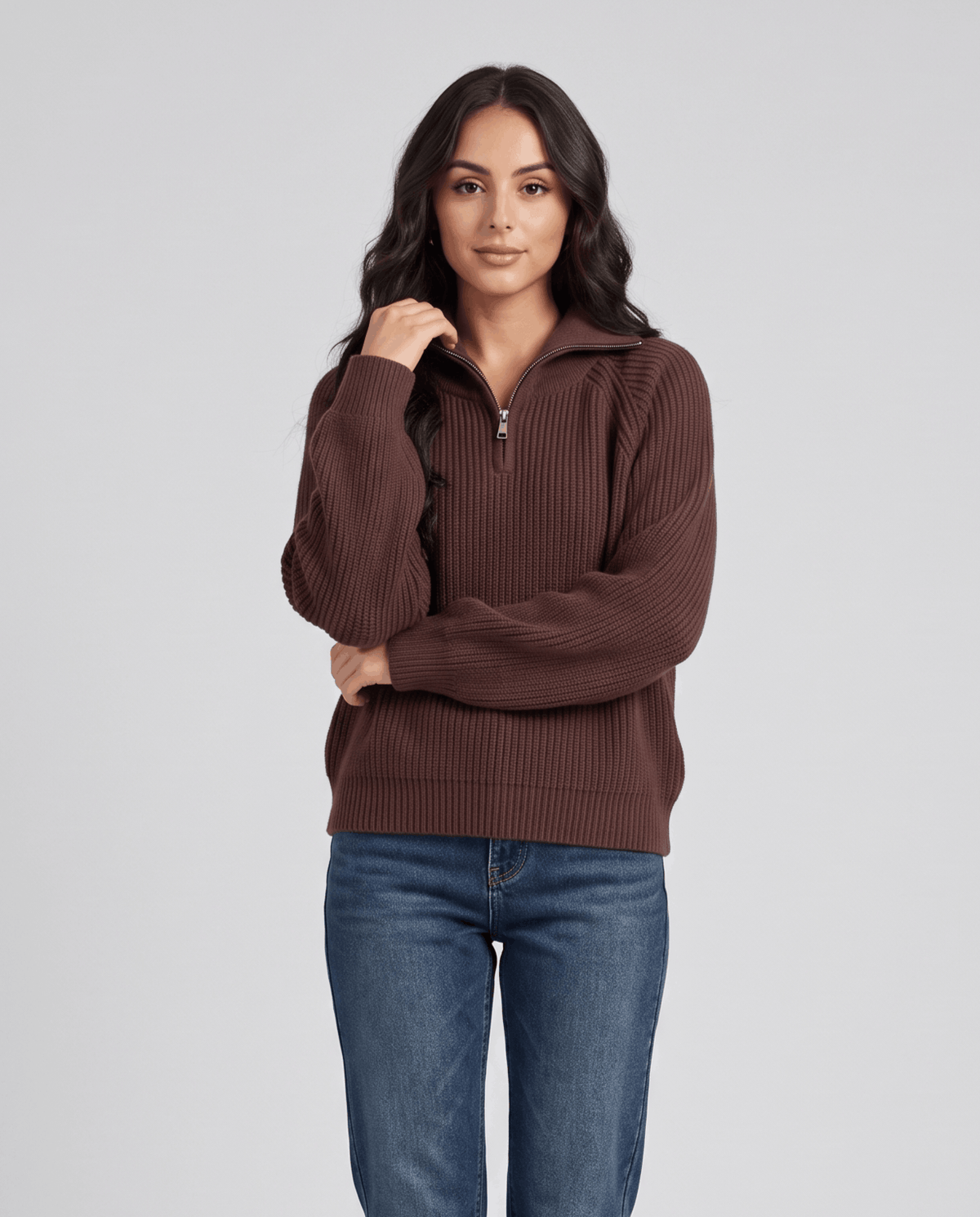 Woman in brown ribbed quarter-zip sweater with arms crossed and blue jeans
