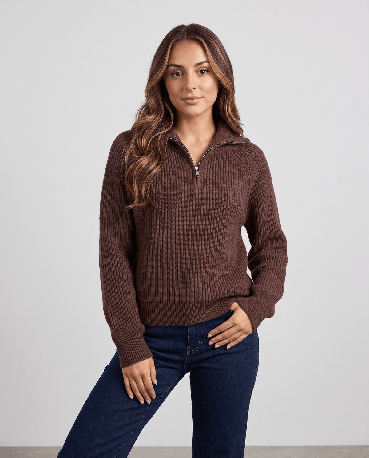 Brown quarter-zip sweater styled with dark jeans, hands in pockets