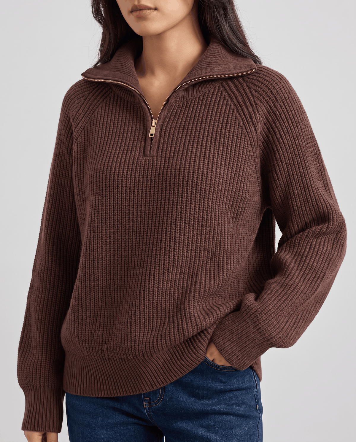 Brown sweater with the quarter-zip open and hand in a jean pocket