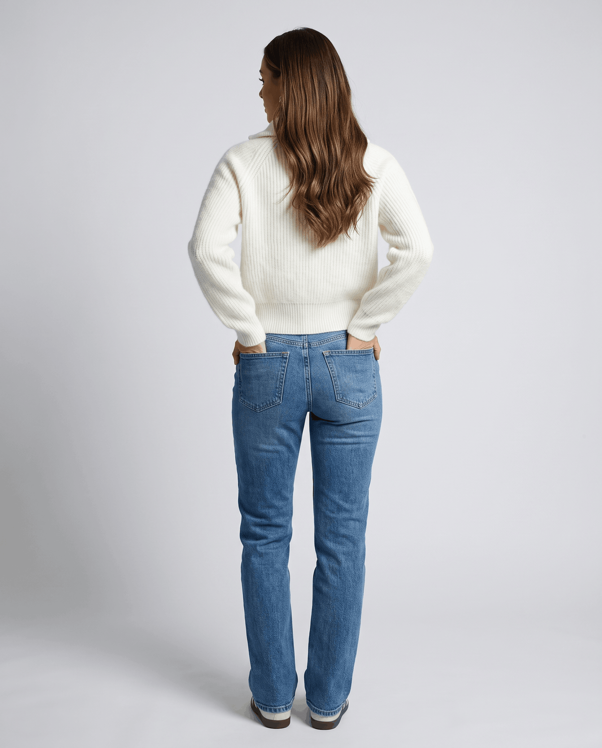 Back view of cream sweater with straight-leg blue jeans