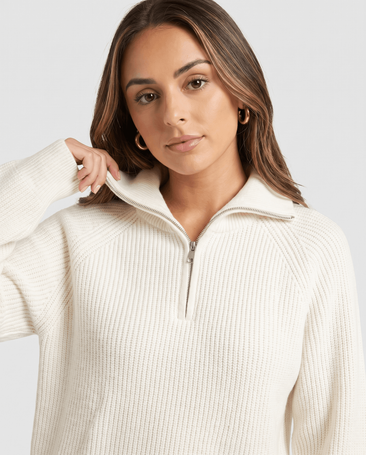 Close-up of model holding the spread collar of a cream quarter-zip sweater