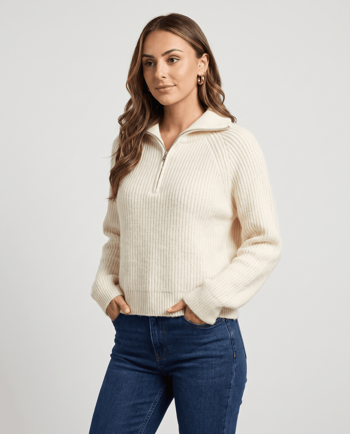 Cream sweater worn with the collar folded down and hands in jean pockets