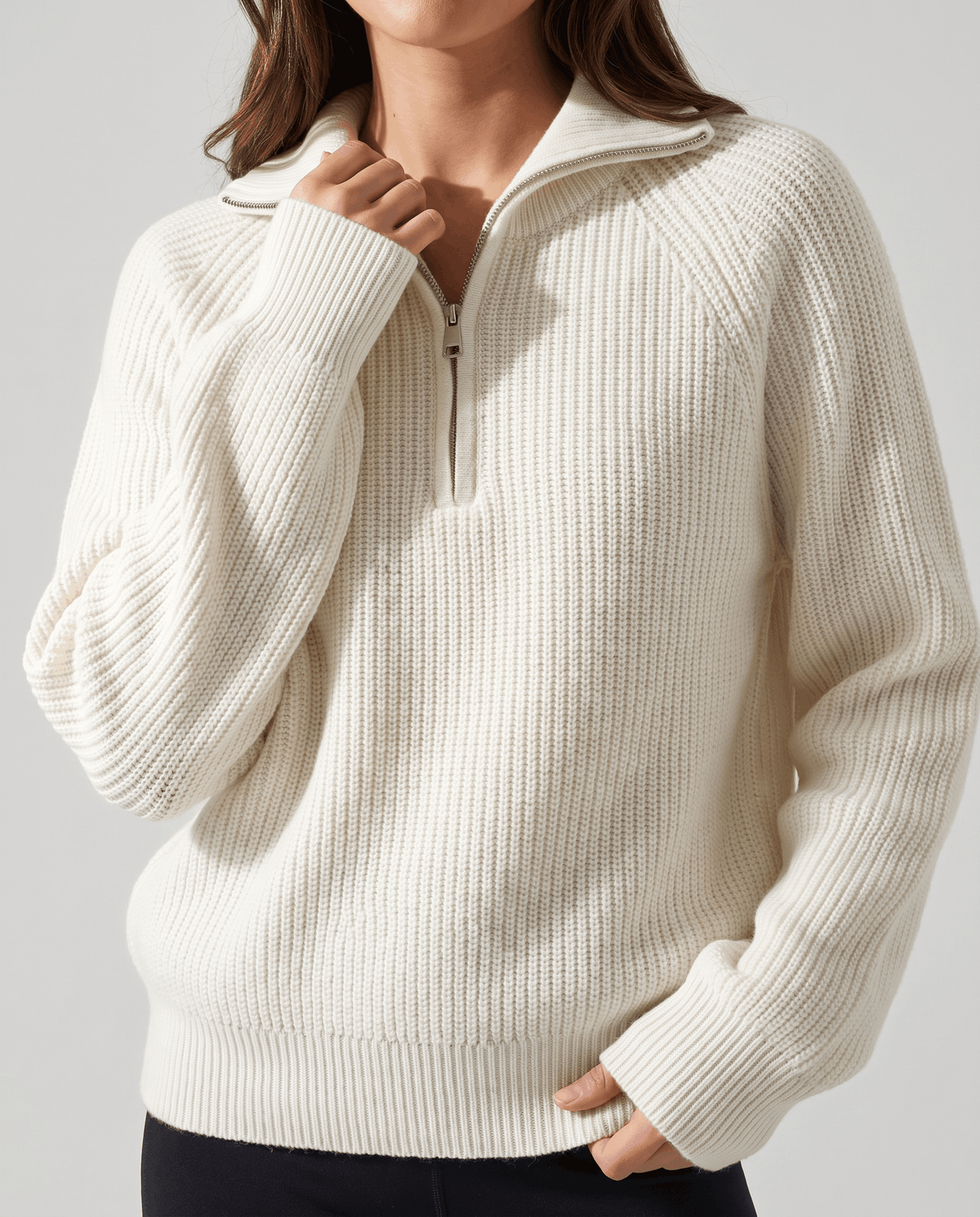 Close-up of the metal quarter-zip and ribbed knit on a cream sweater