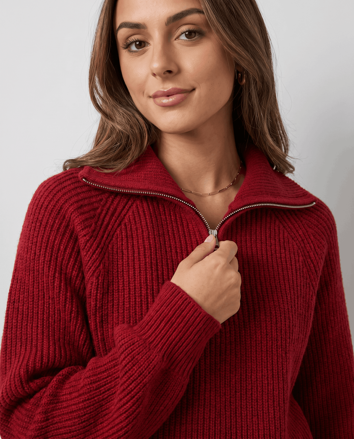 Model holding the zip pull of a red quarter-zip sweater