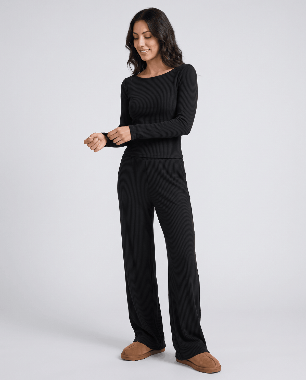 Black long-sleeve top and wide-leg pants worn with hands near the cuff, front view