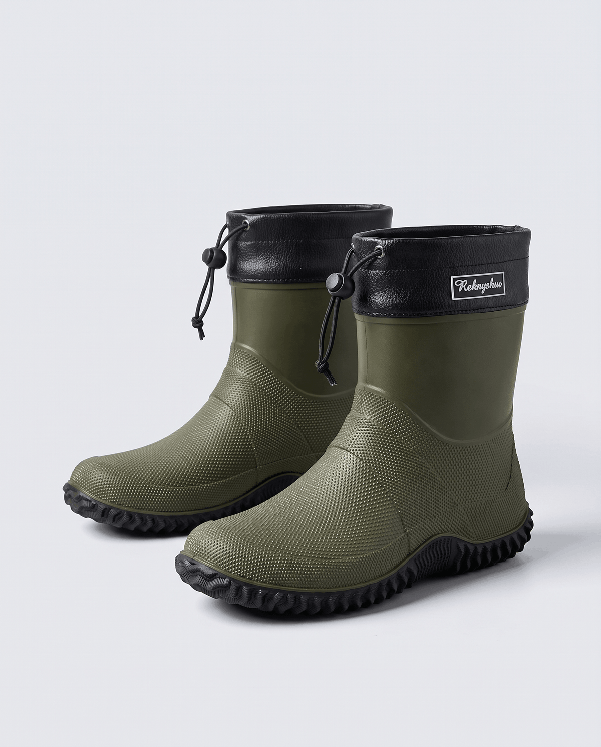 Two army green rubber boots with black collars and deep lug soles on grey
