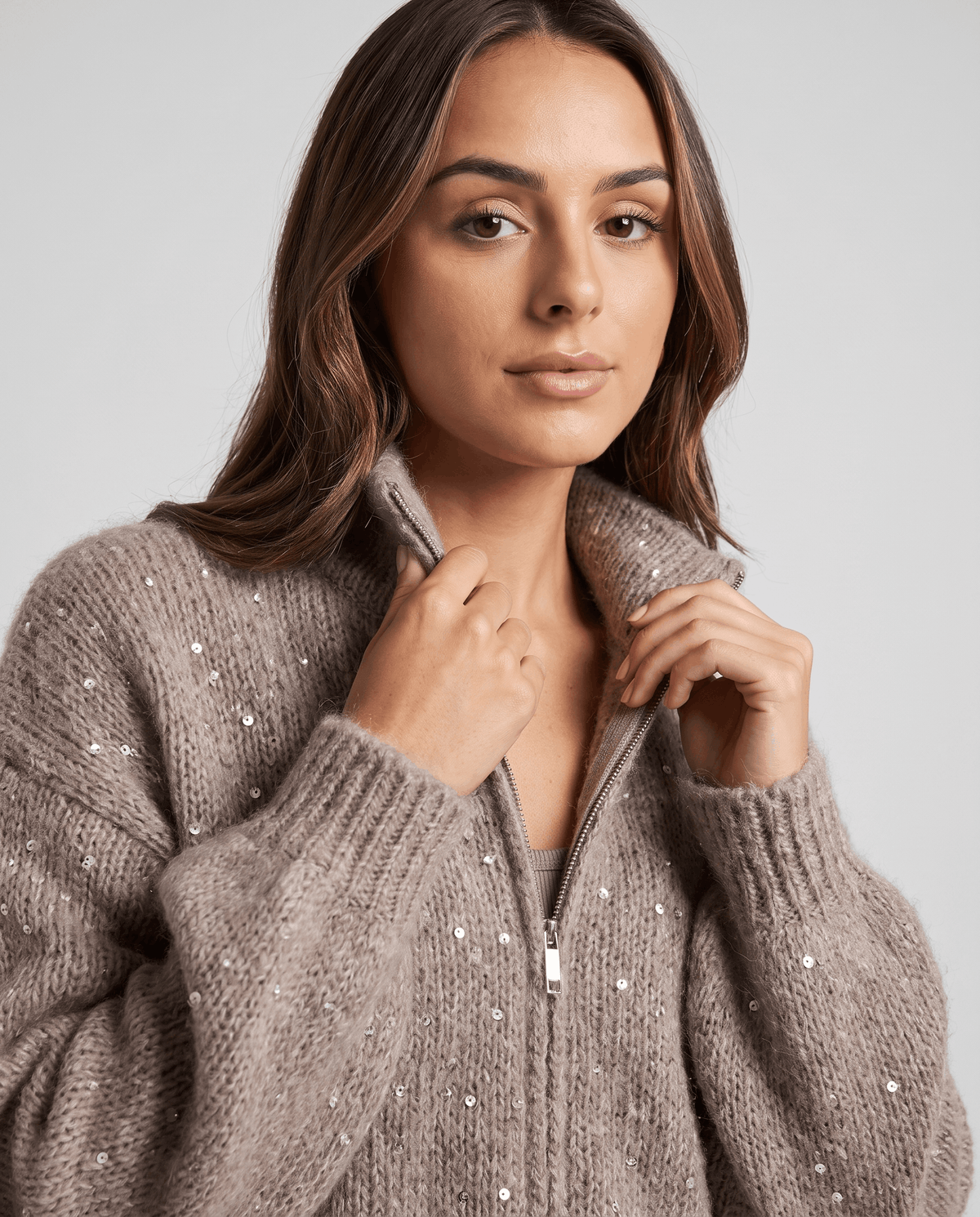 Close-up of the brown knit cardigan with hands framing the fold-over collar