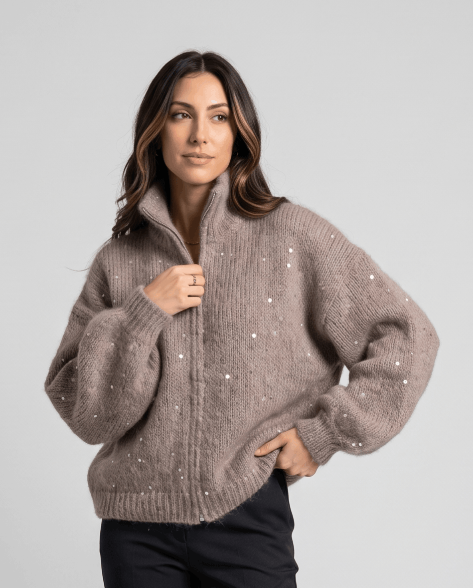 Brown cardigan half-zipped with one hand at the collar and one on the hip