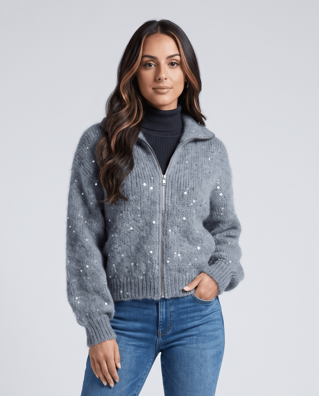Waist-up gray cardigan with fold-over collar and scattered sequins, hand in jean pocket