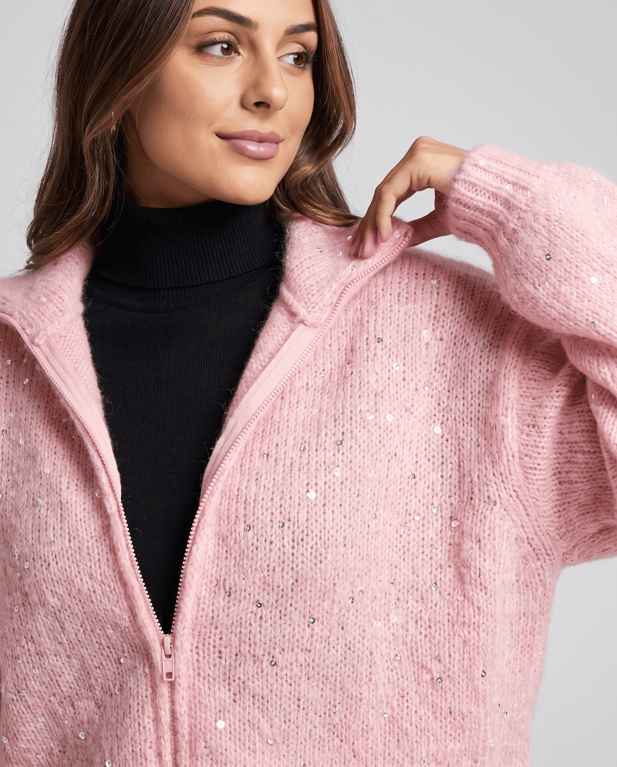 Close-up of the pink knit cardigan collar and zip worn over a black turtleneck