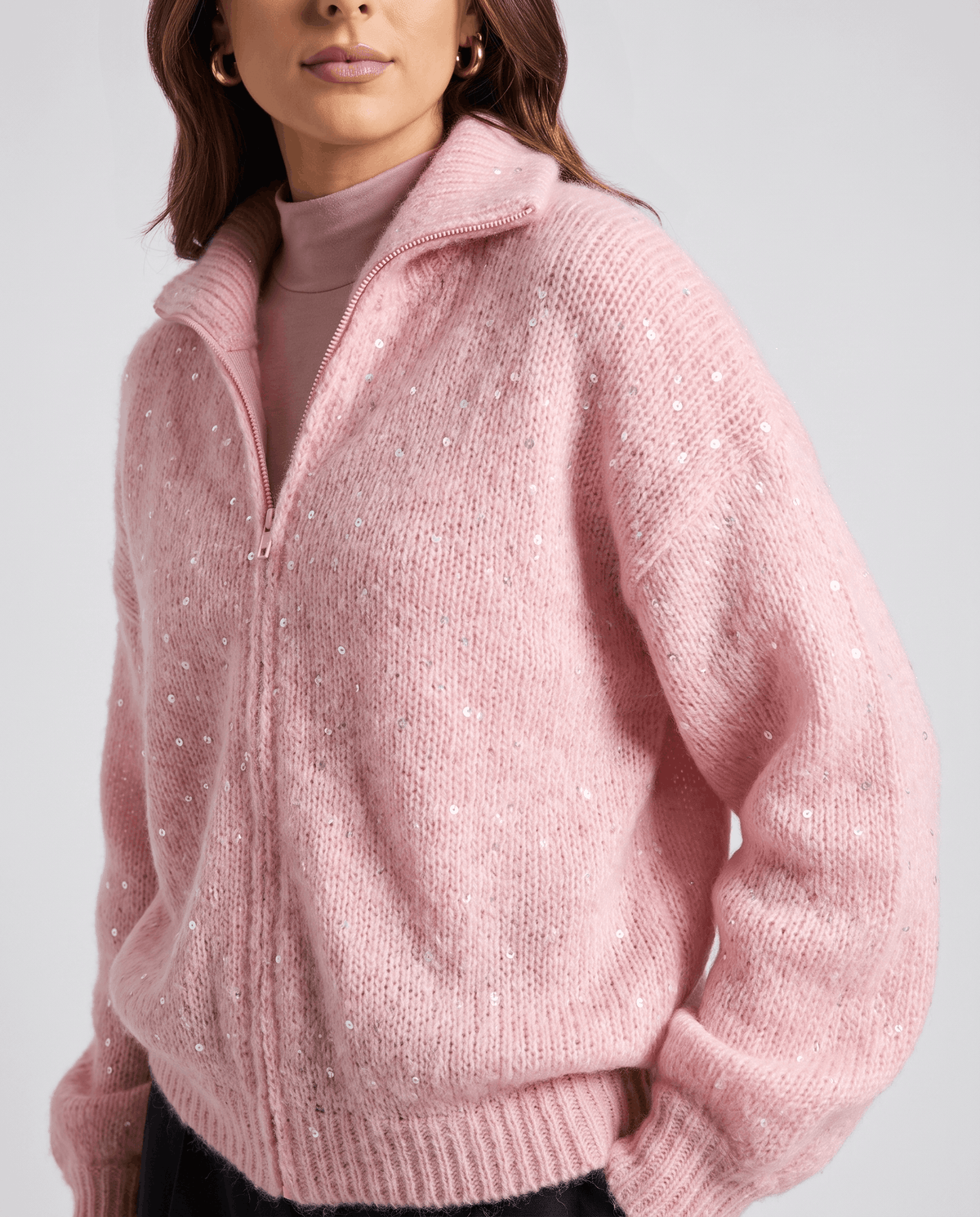 Pink fuzzy knit cardigan zipped over a pink turtleneck, showing scattered sequin detail