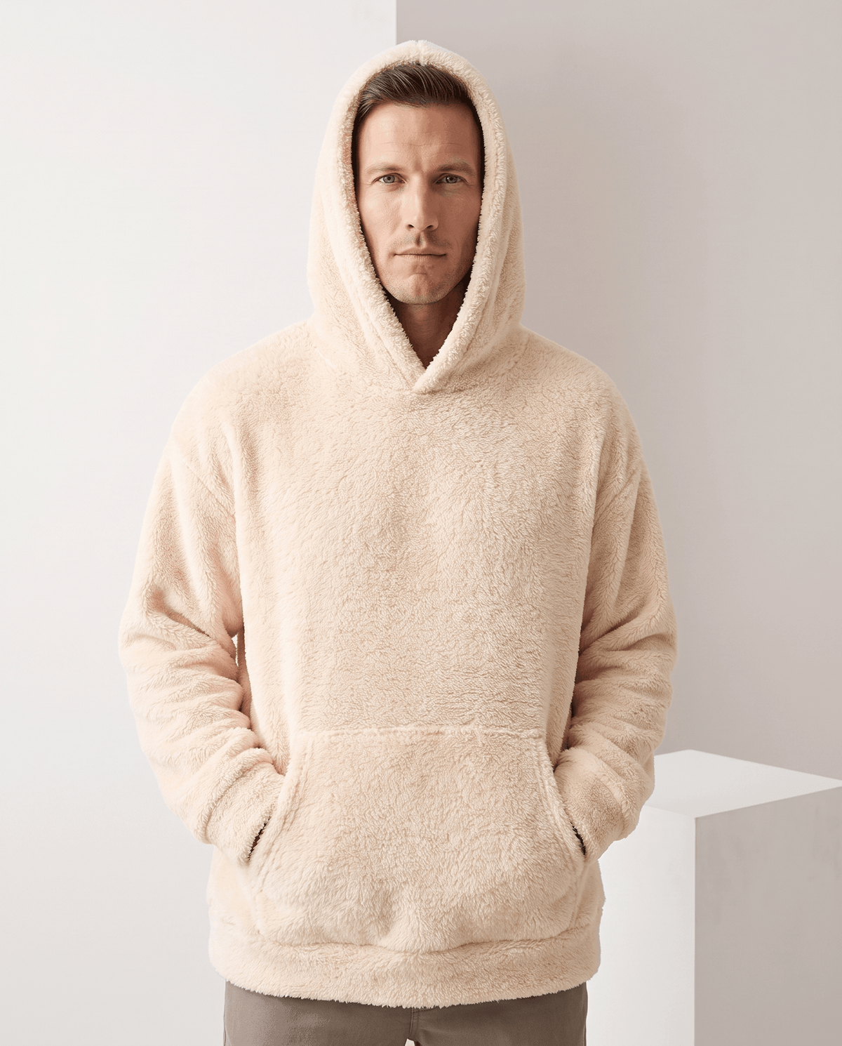 Front view of the beige hoodie worn with the roomy hood pulled up