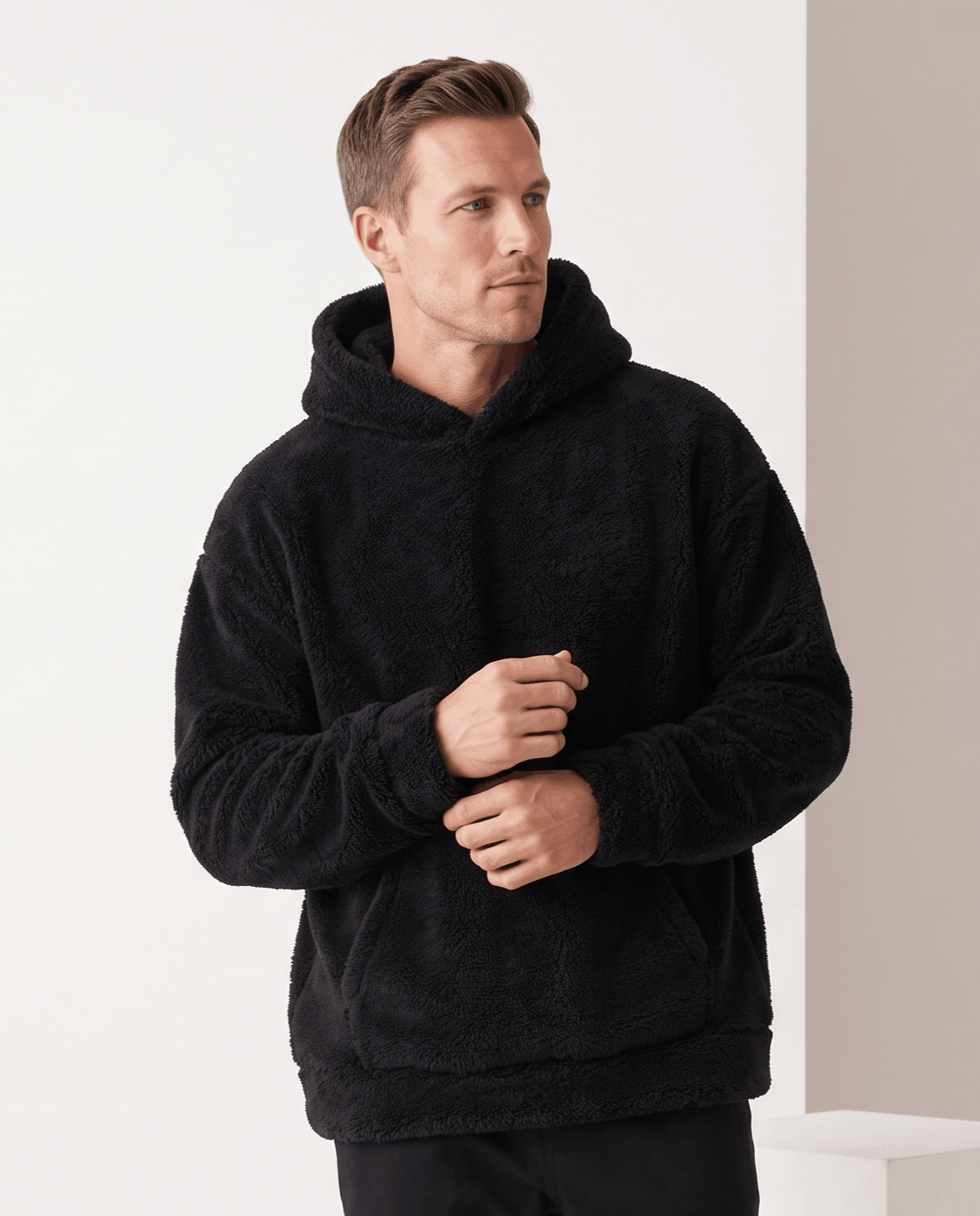 Black plush hoodie front view with hands together at the chest