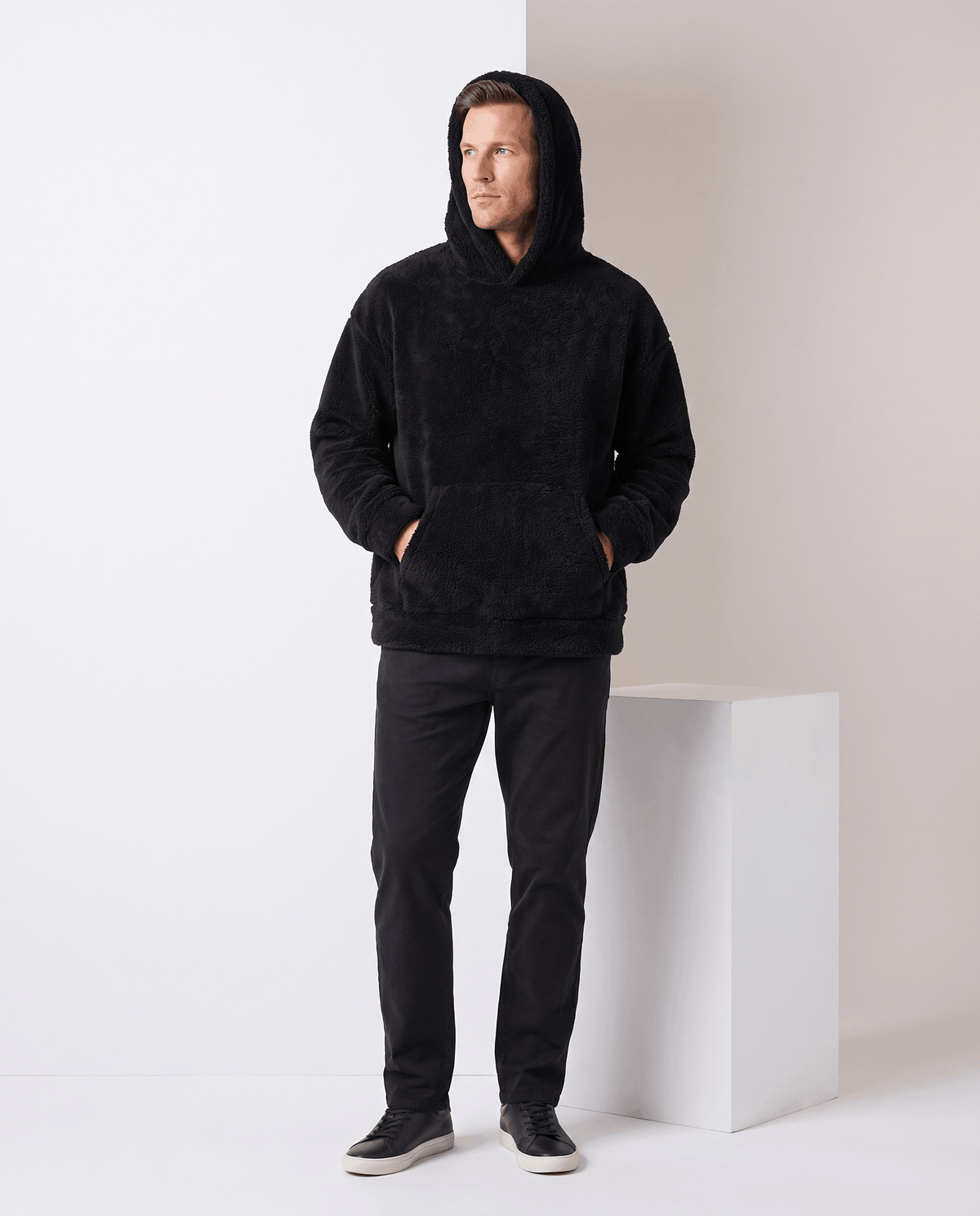 Full-length view of the black hoodie worn with the hood up and black jeans