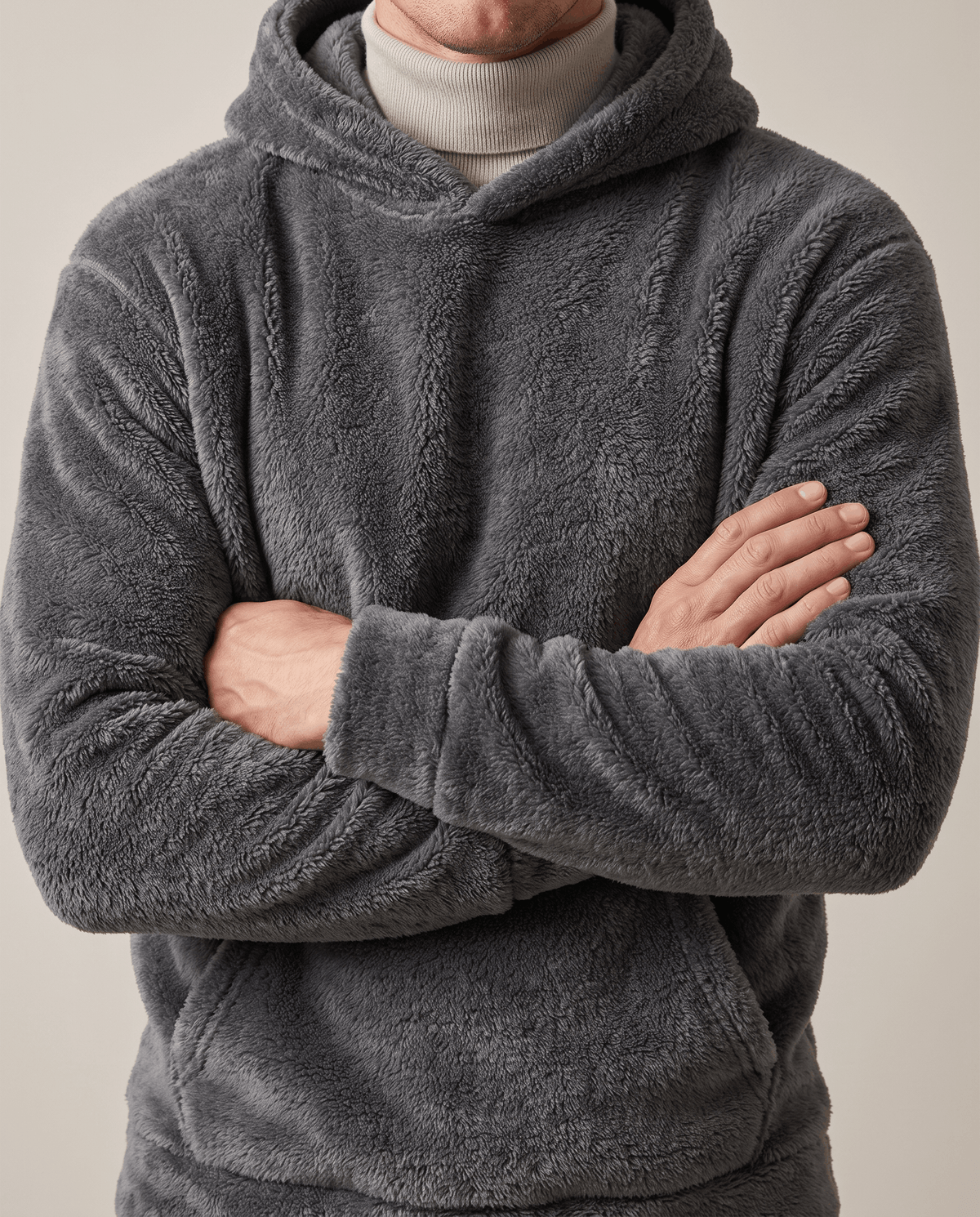 Gray fuzzy hoodie over a cream turtleneck with arms crossed