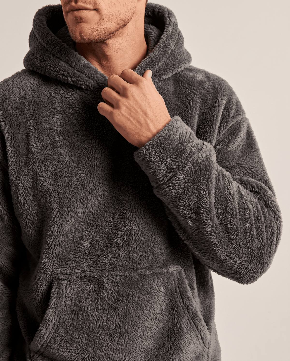 Close-up of a hand at the hood of the gray plush pullover hoodie