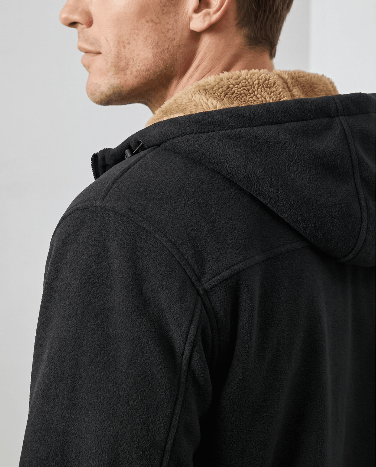 Shoulder and hood detail of the black hoodie with tan sherpa lining