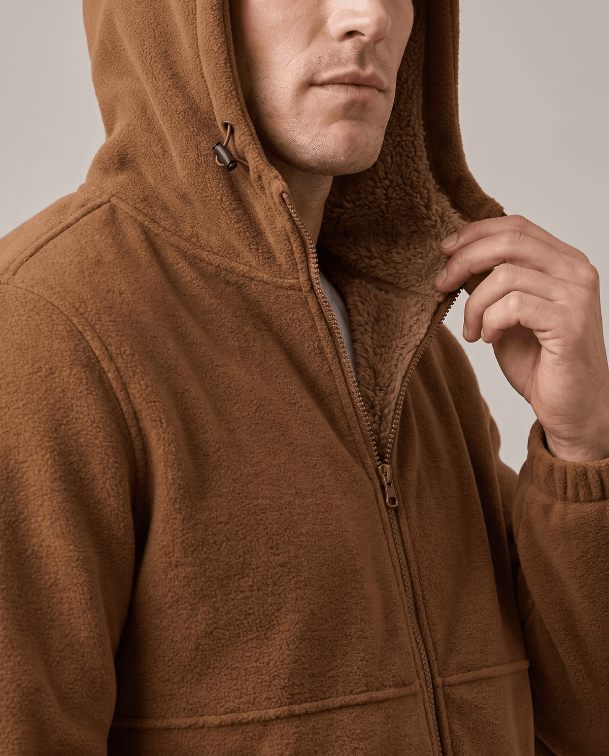 Close-up of a hand at the sherpa-lined hood of the khaki hoodie