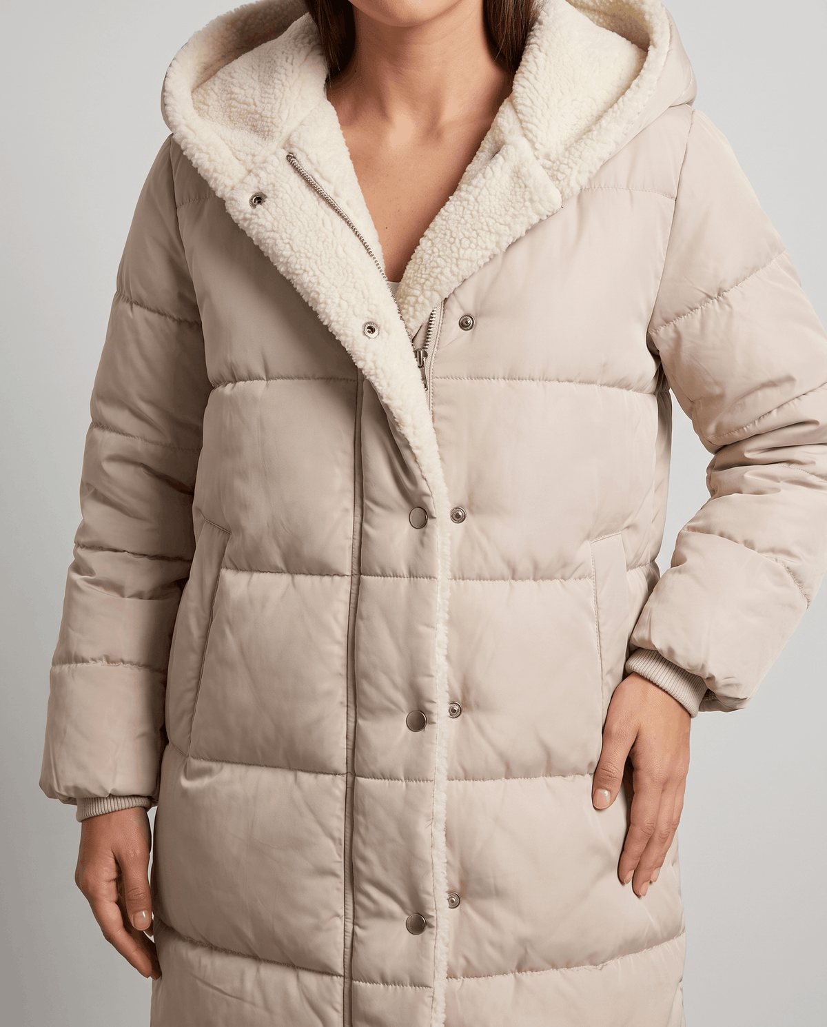 Close-up of beige coat snap placket and sherpa-trimmed hood