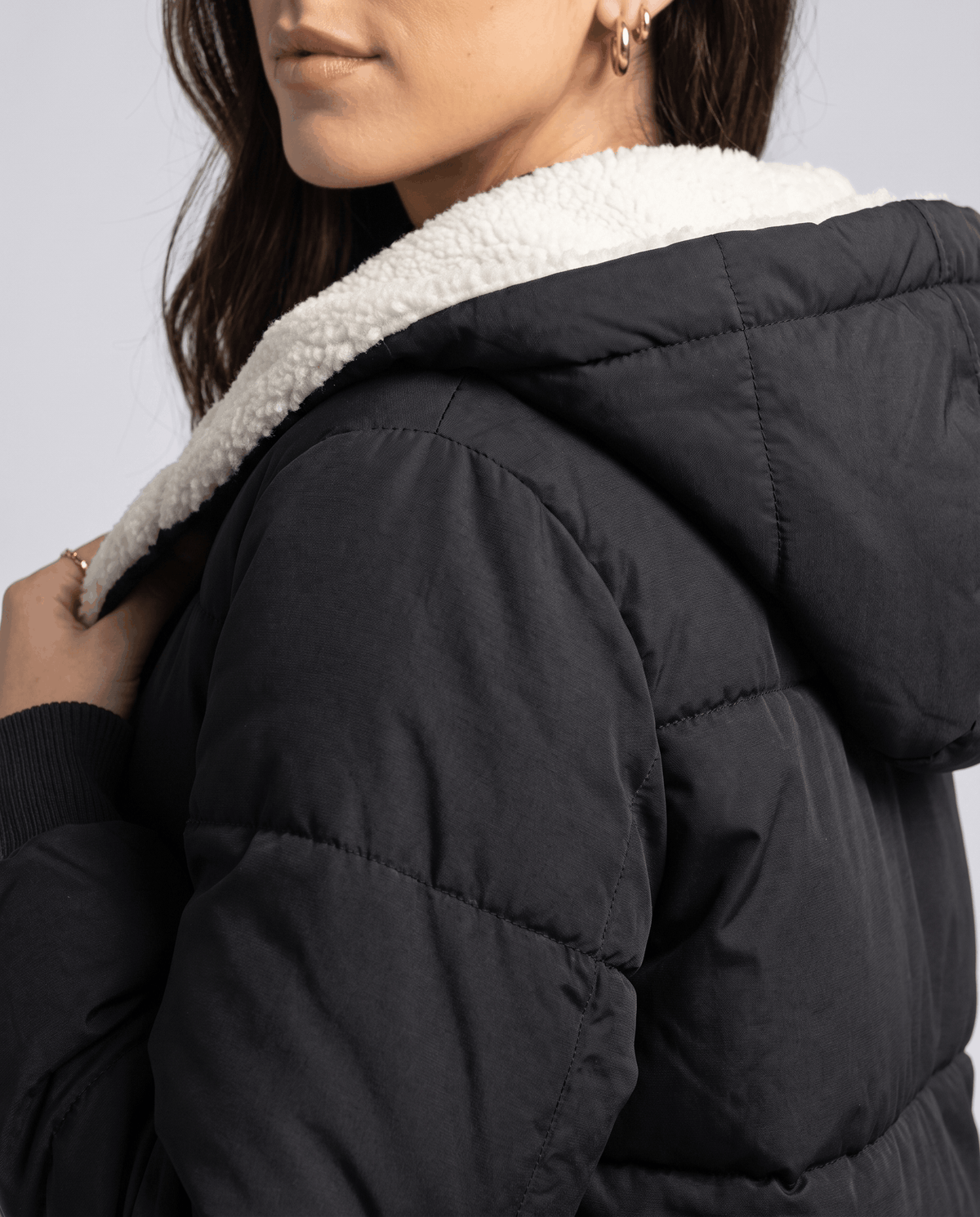 Close-up of the cream sherpa hood lining on a black puffer coat
