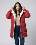 Woman in red sherpa-lined hooded puffer coat holding the hood, with blue jeans