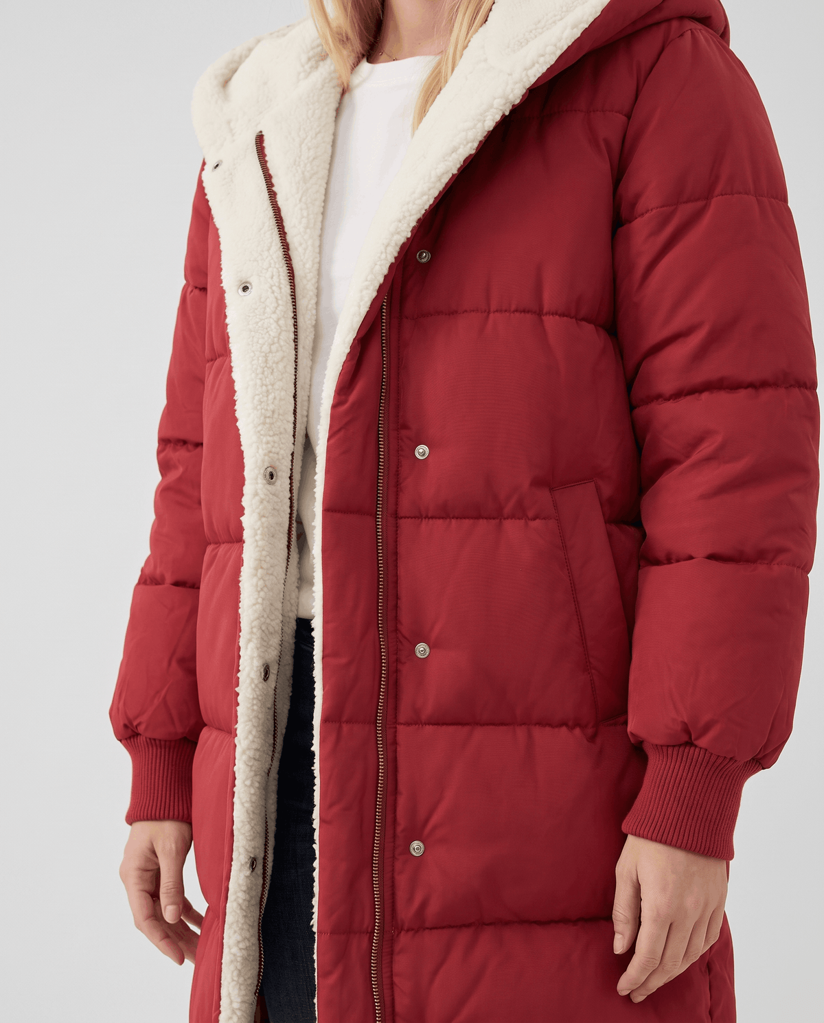 Red coat worn open showing sherpa front facing and ribbed knit cuffs