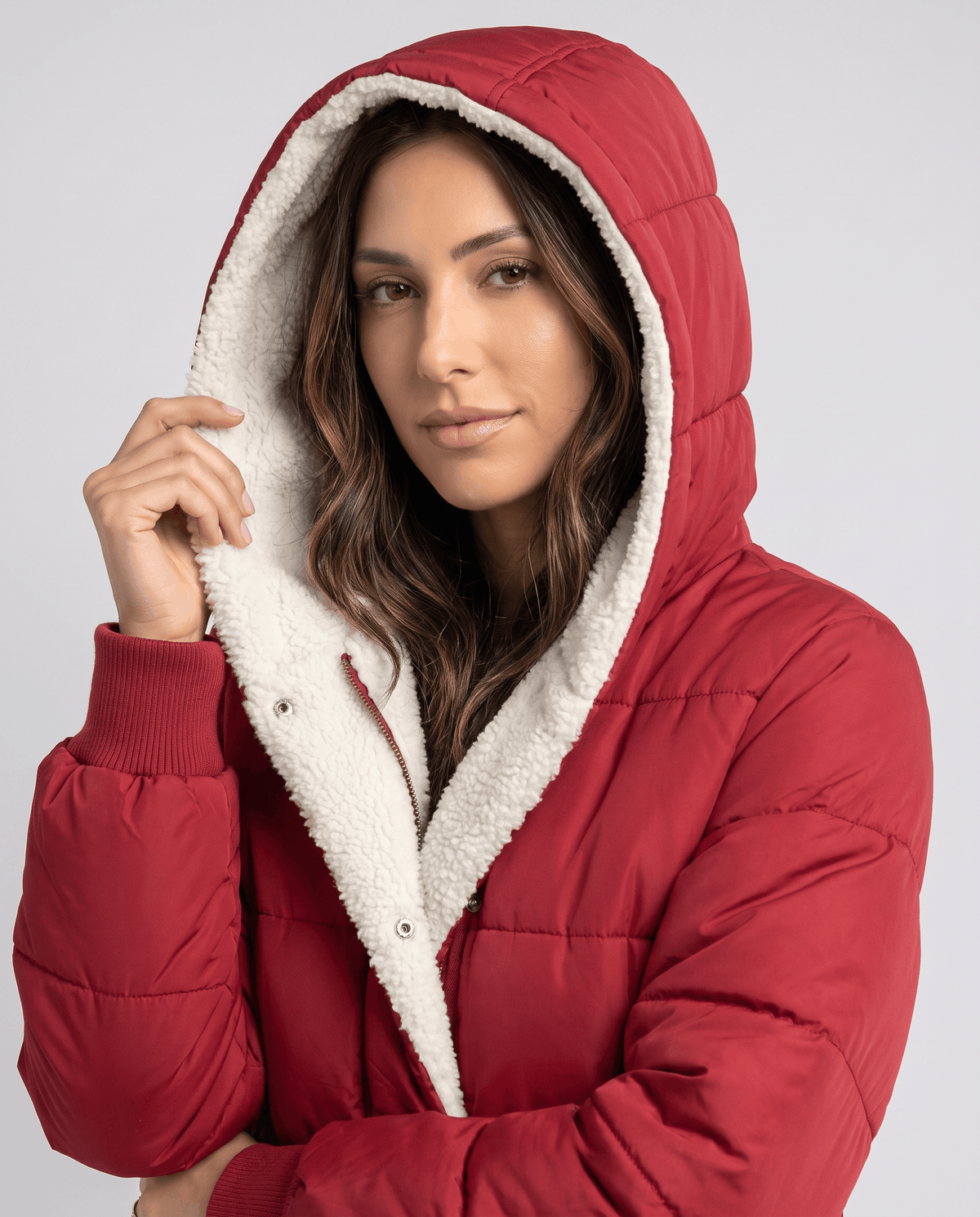 Model wearing the sherpa-lined hood up on a red puffer coat