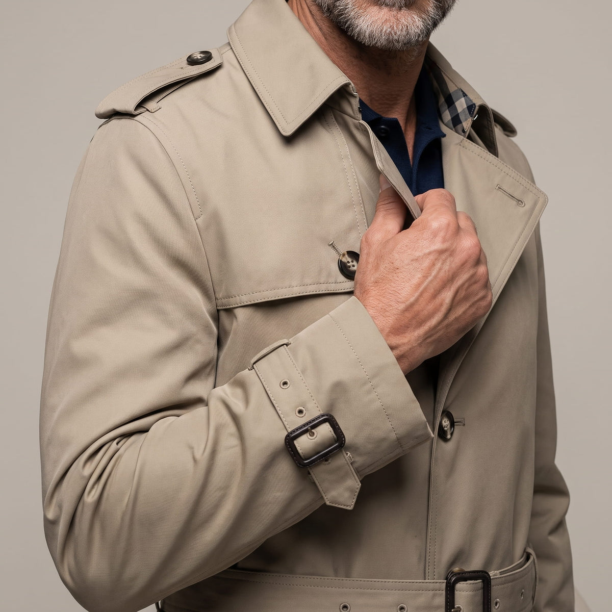 Close-up of beige trench coat collar, epaulet and cuff strap buckle