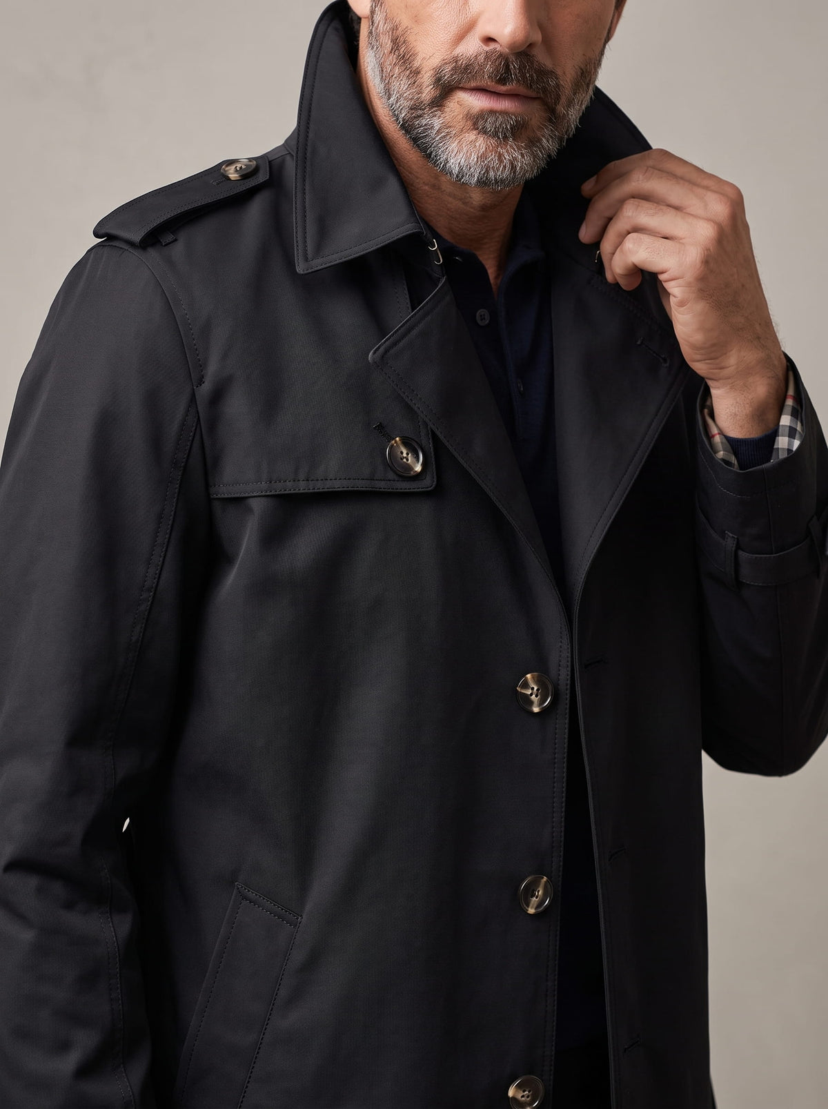 Close-up of black trench coat front buttons, epaulet and collar