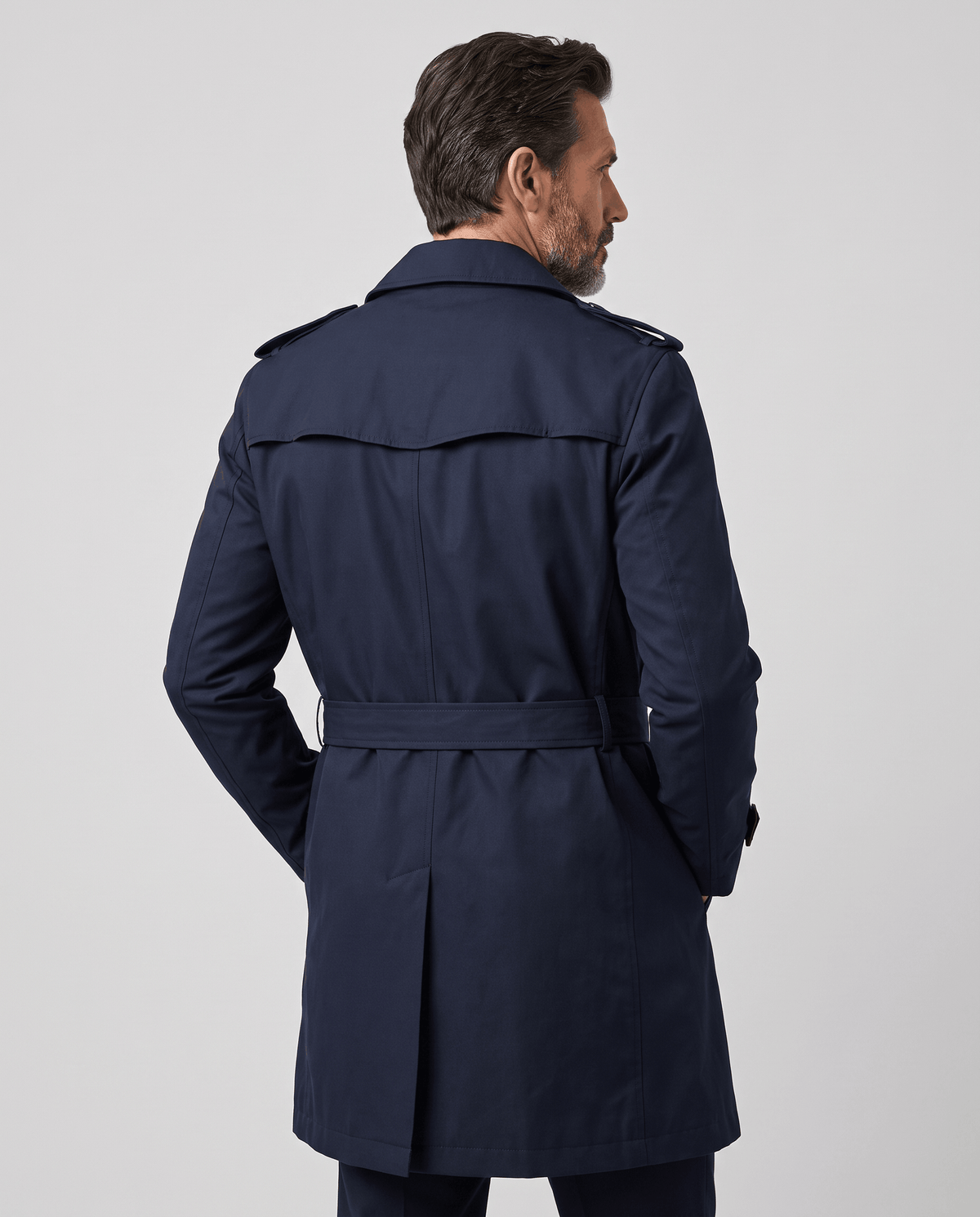Back view of navy trench coat with storm yoke, epaulets and tied belt