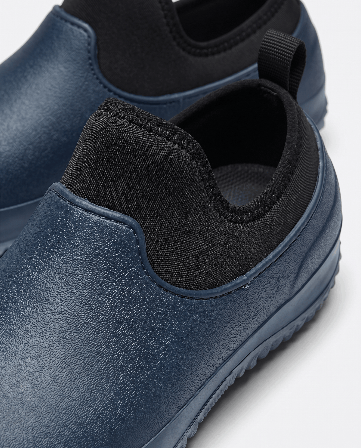 Close view of navy blue molded upper and black stretch collar with pull loop