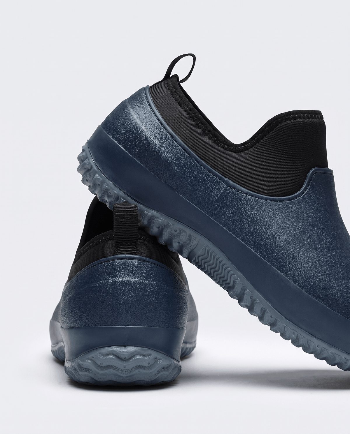 Navy blue shoes with deep tread grey soles, one tilted to show the sole