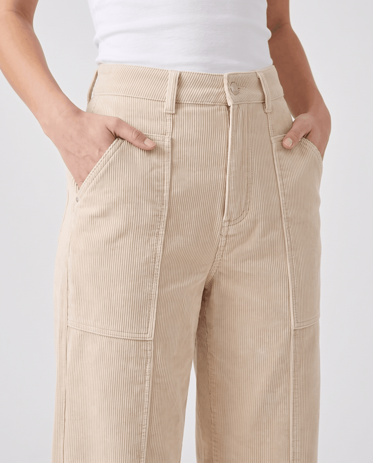 Close-up of the cream button front with seamed patch pockets and hands in the side pockets