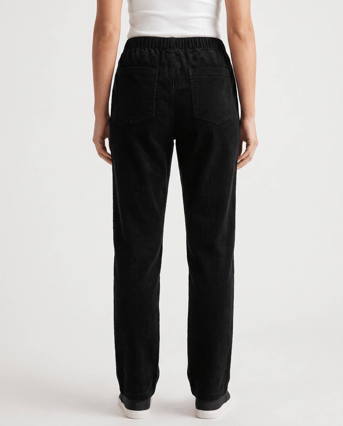 Back view of black corduroy pants showing the elastic waistband and straight ankle-length leg