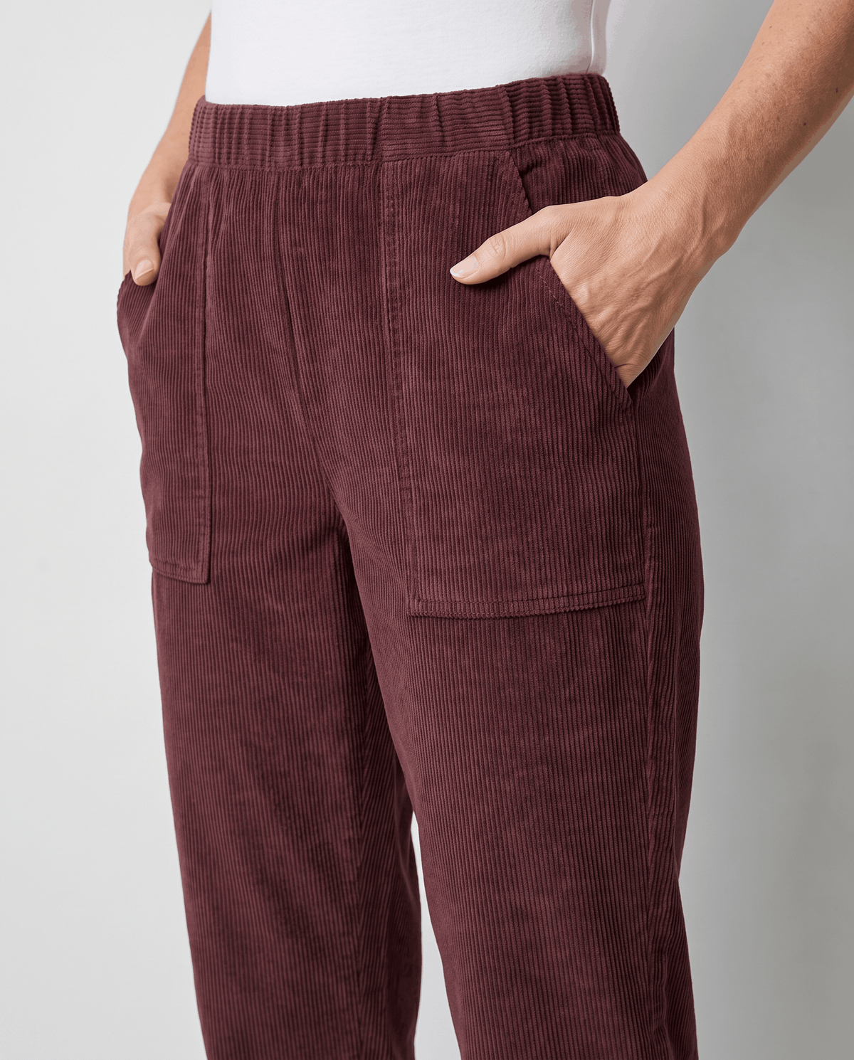 Close-up of burgundy corduroy front with slant hand pockets, patch pockets and elastic waist