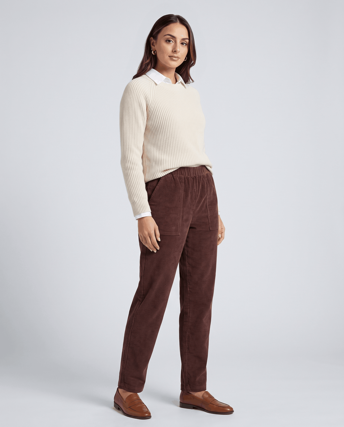 Model in burgundy ribbed trousers styled with a cream sweater, white collar and brown loafers