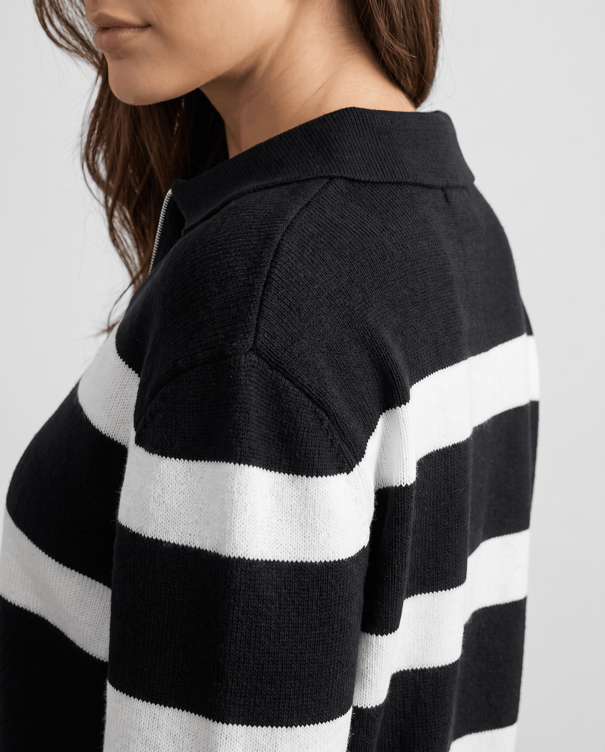 Shoulder detail of black knit with white stripes and pointed polo collar