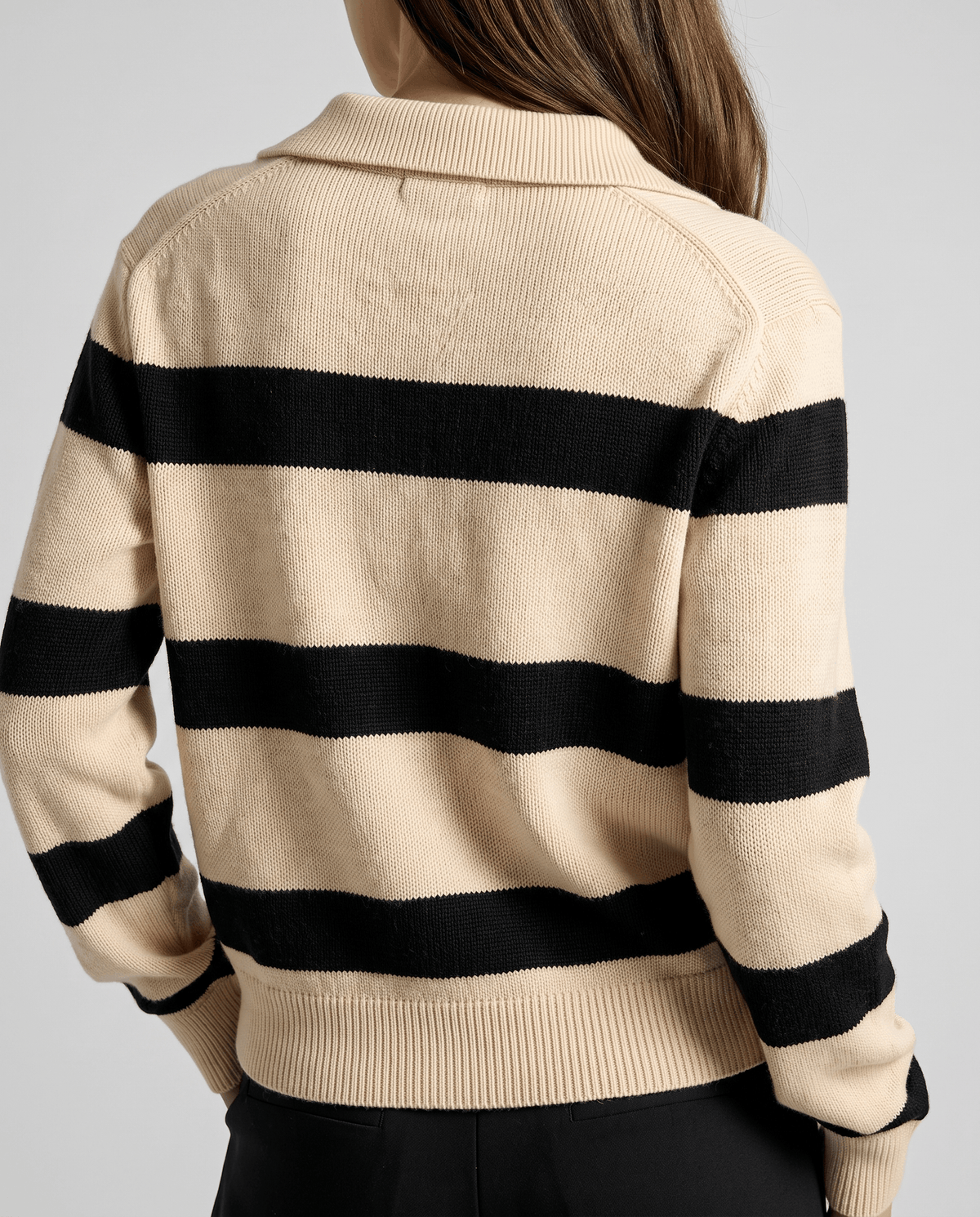 Back view of beige and black striped sweater showing ribbed cuffs and hem