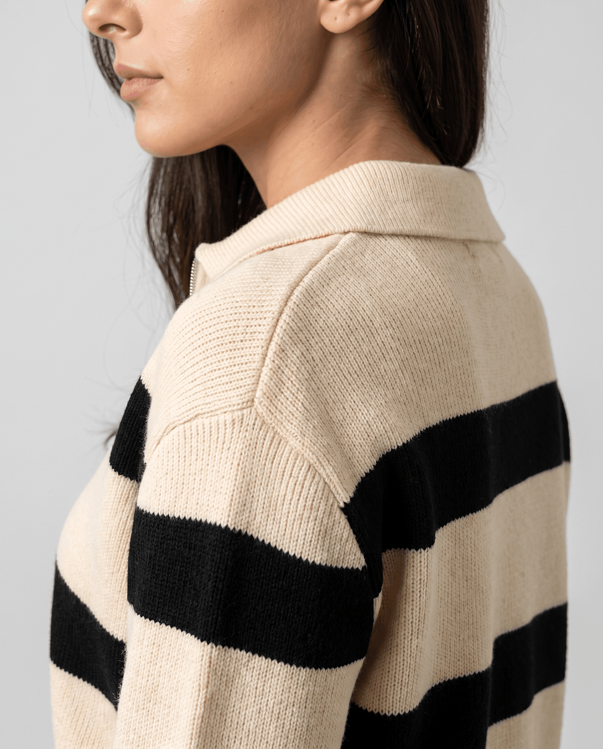 Side shoulder detail of beige knit with wide black stripes and pointed collar