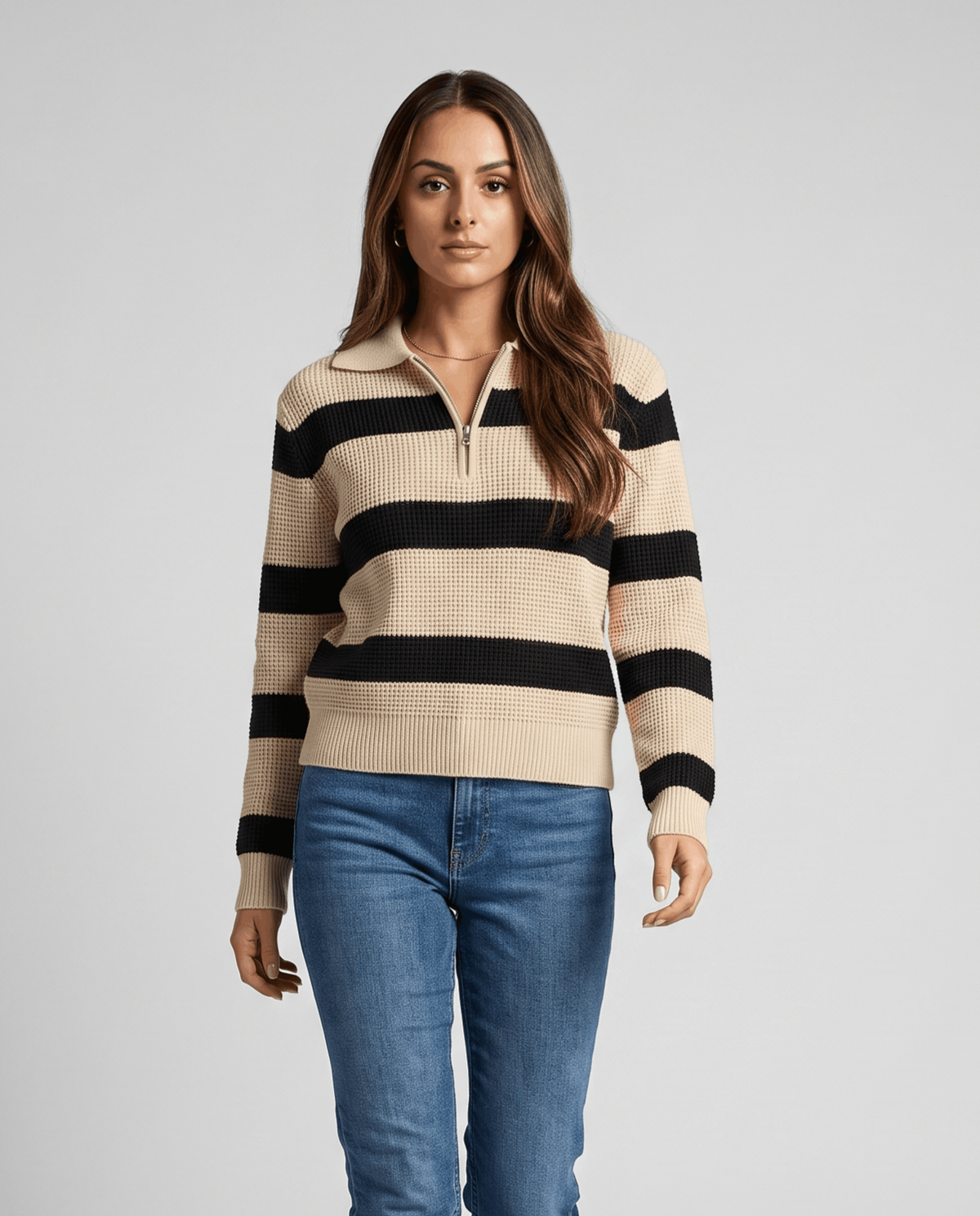 Woman wearing a beige and black striped half-zip polo sweater with light jeans
