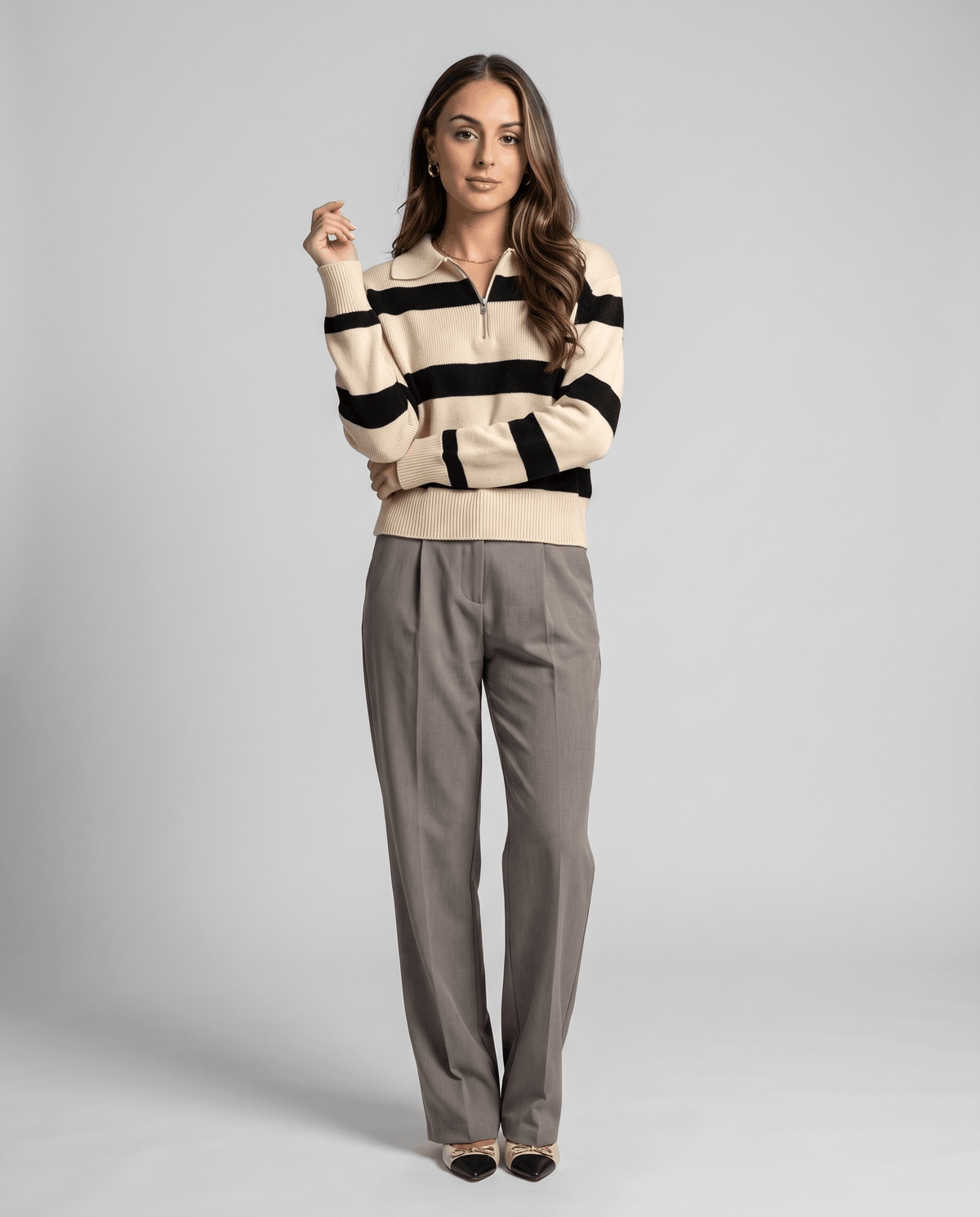 Full-length view of beige striped pullover styled with gray wide-leg trousers