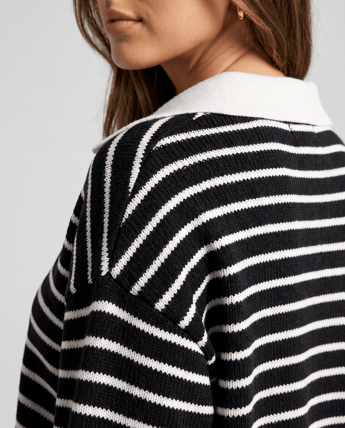 Detail of the white collar and stripes on the back of a black knit top