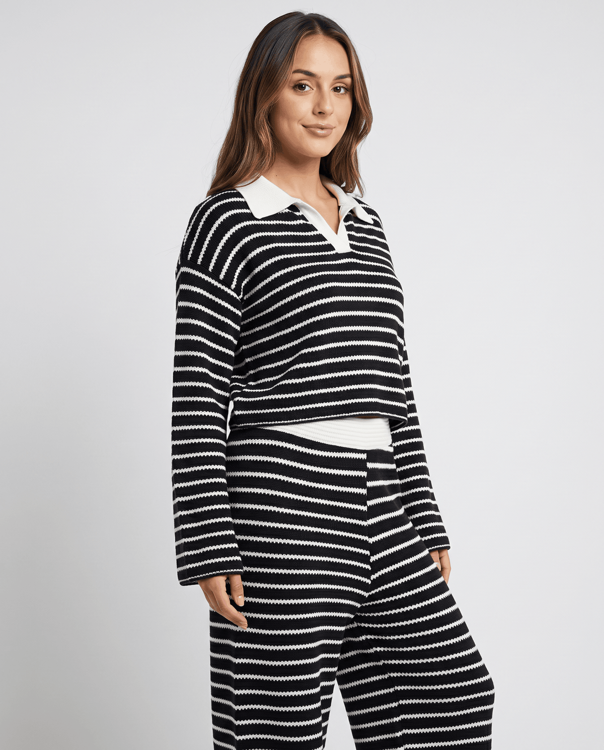 Side view of woman in black striped knit top with white collar and pants
