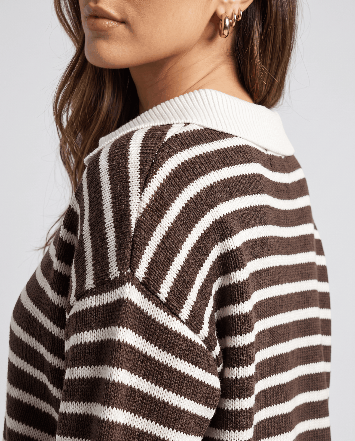 Close-up of the white collar and brown stripes on a drop-shoulder knit top