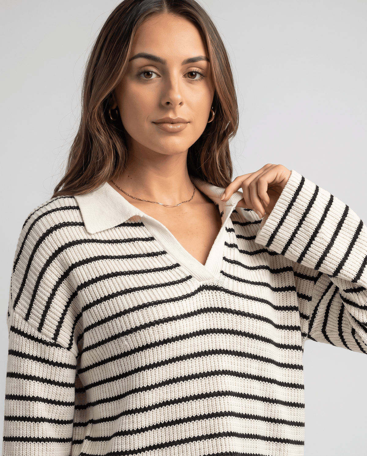 Close-up of cream knit top with black stripes and a folded V-neck collar