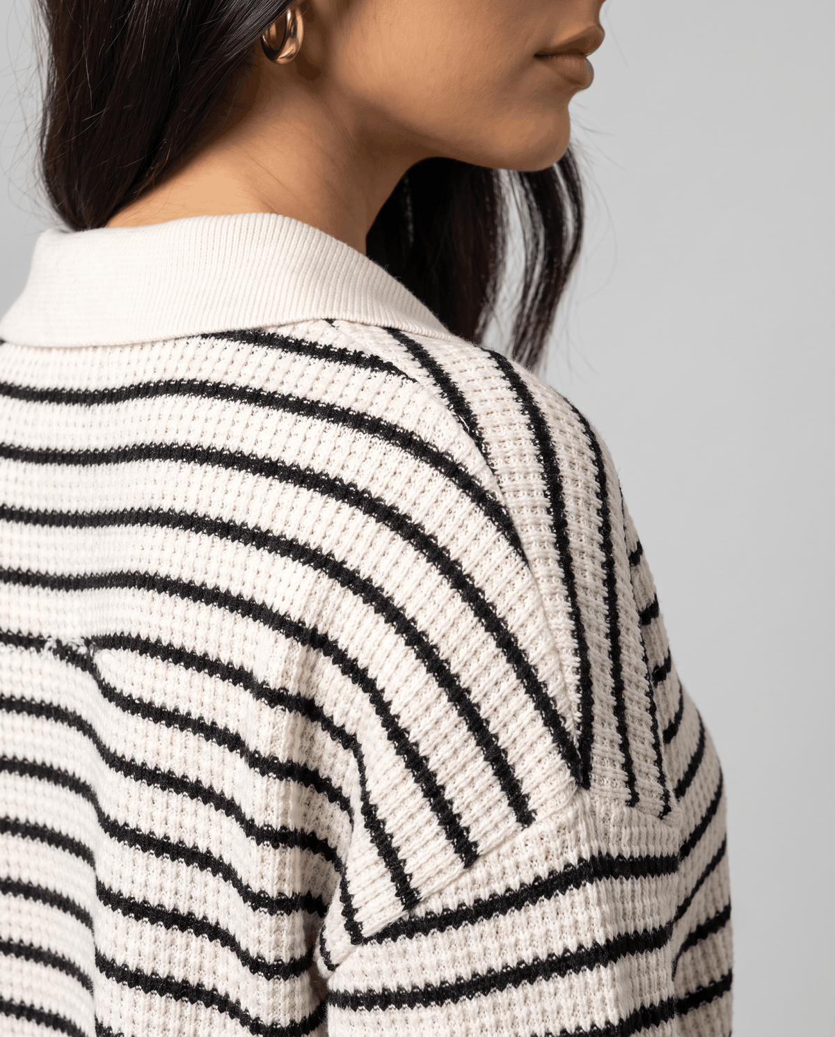 Detail of the collar and black stripes on the back of a cream knit top