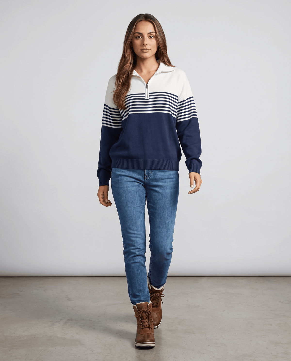 Full-length view of navy color-block pullover with light jeans and brown boots