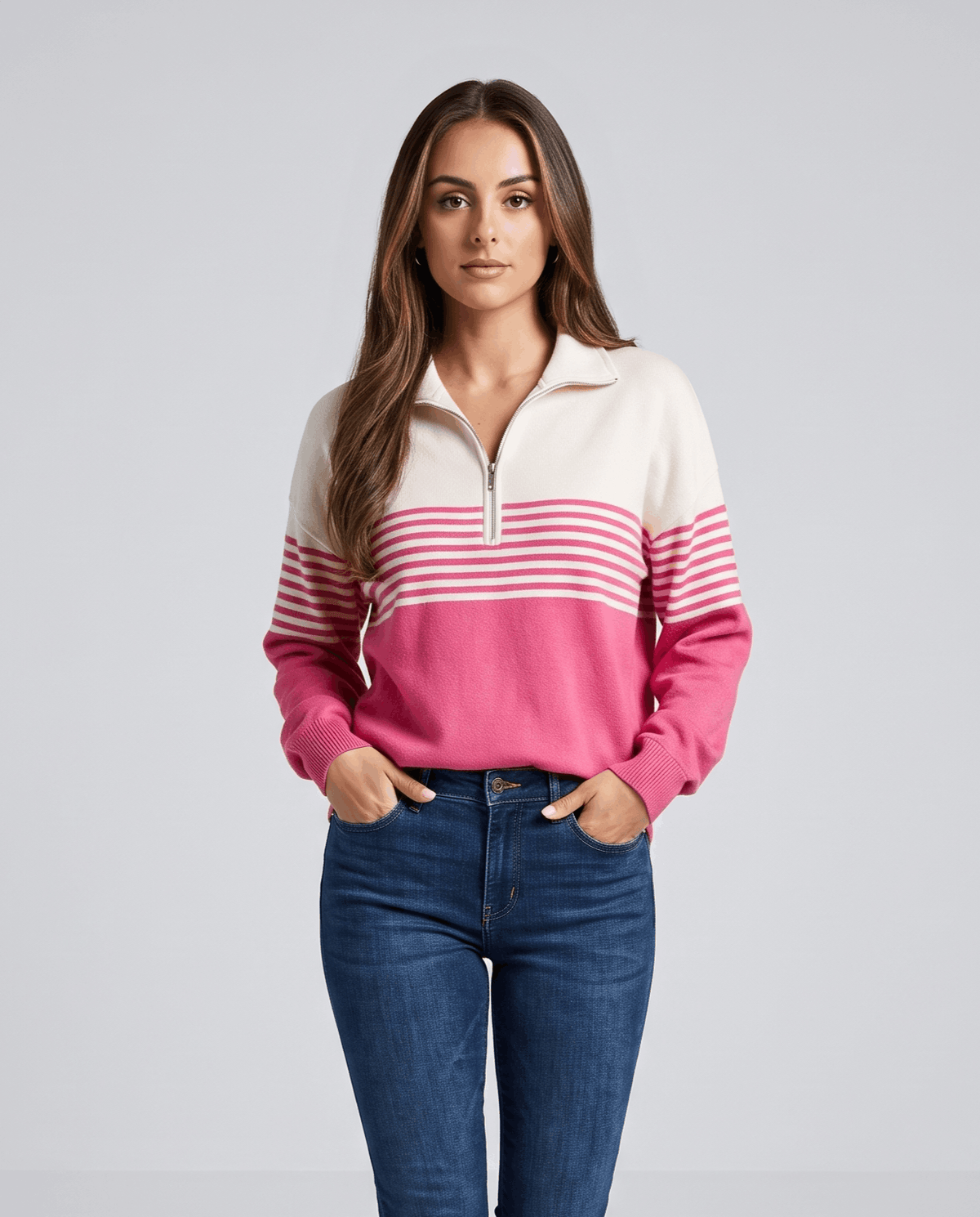 Fuchsia striped knit pullover worn with medium wash jeans against a light gray backdrop