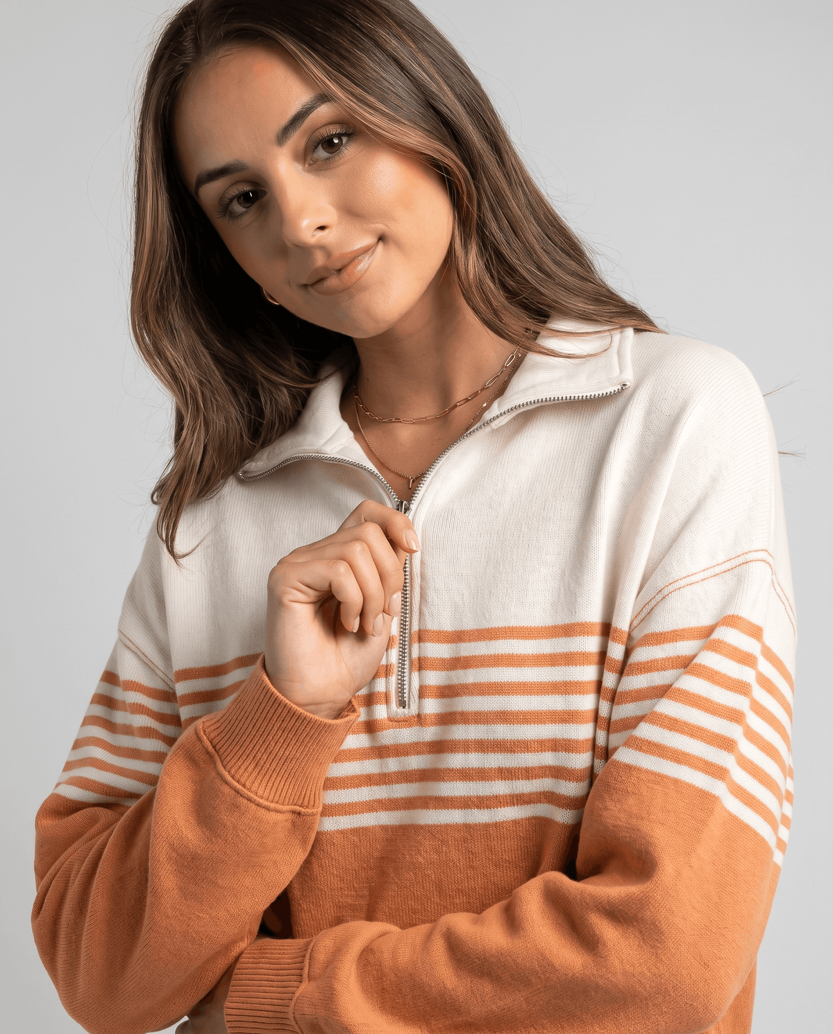 Close-up of model in orange striped pullover showing fold-over collar and zip