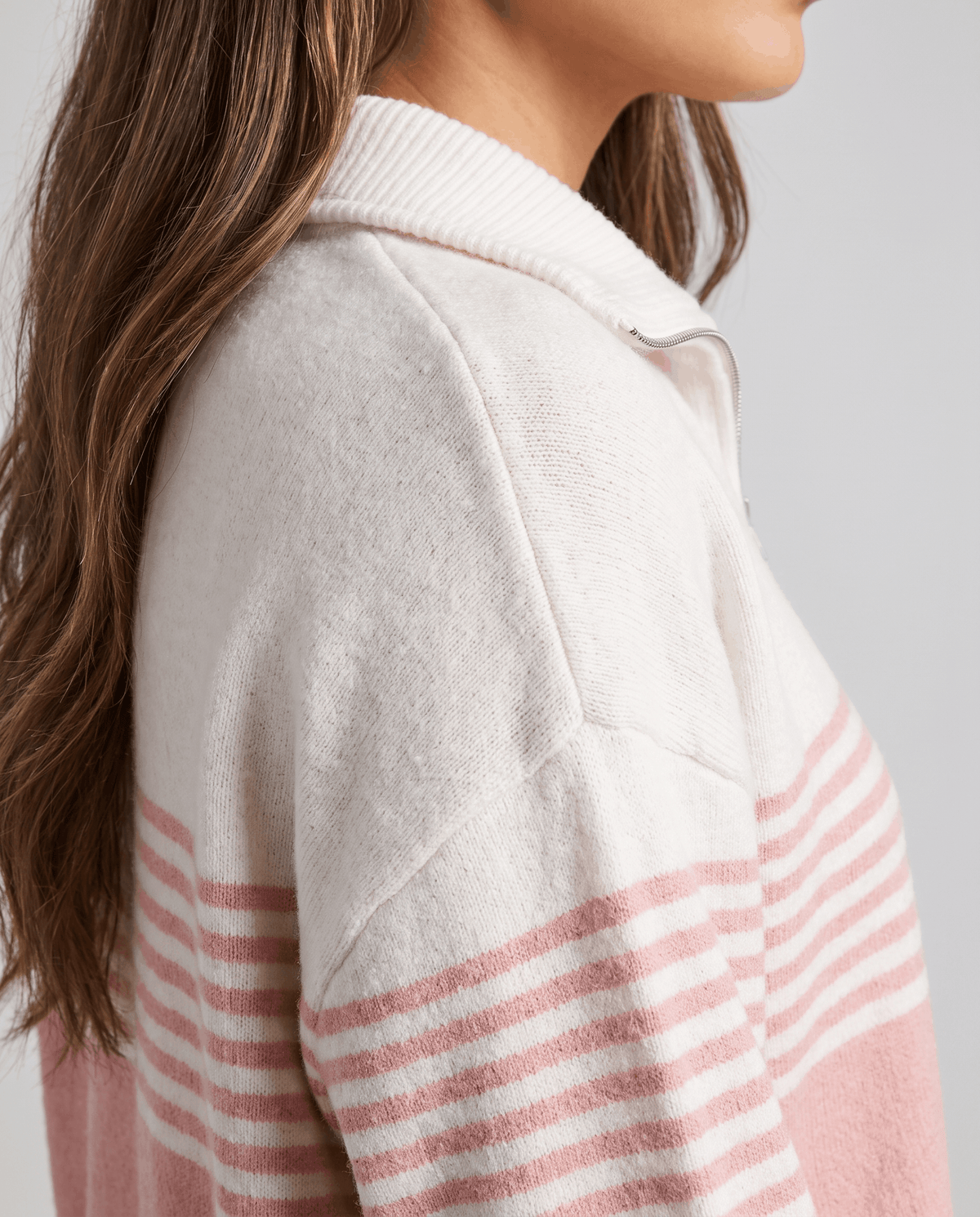 Close-up of soft pink stripes and drop shoulder seam on an ivory knit sleeve